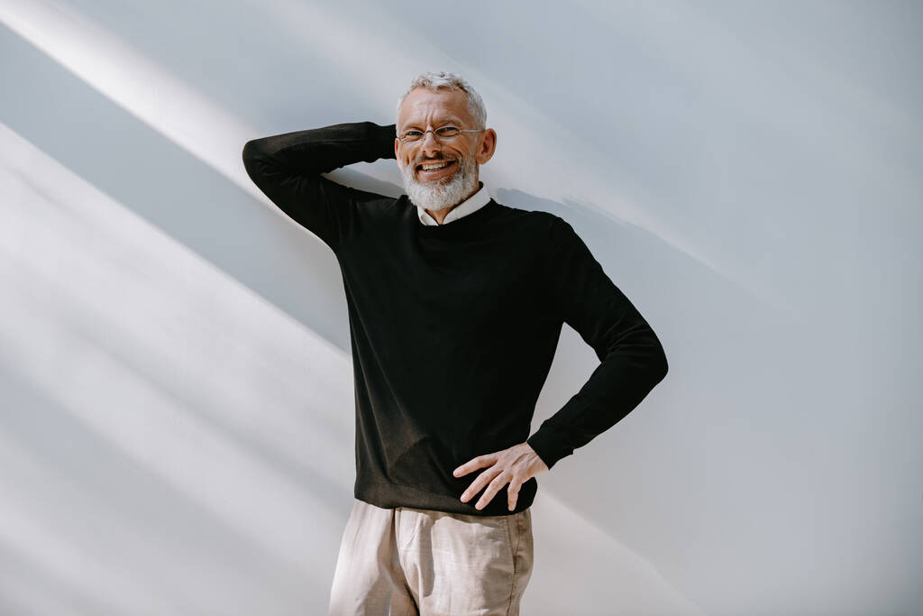 Porträt eines entspannten Seniors in schicker Freizeitkleidung, der die Hand hinter dem Kopf hält und sich an die Wand lehnt - Foto, Bild