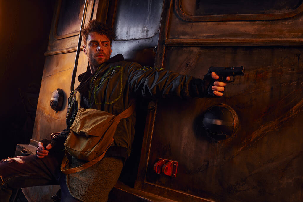 Небезпечний чоловік ховається за вагоном і прицілюється з пістолетом у покинутому метро, після катастрофи виживання - Фото, зображення