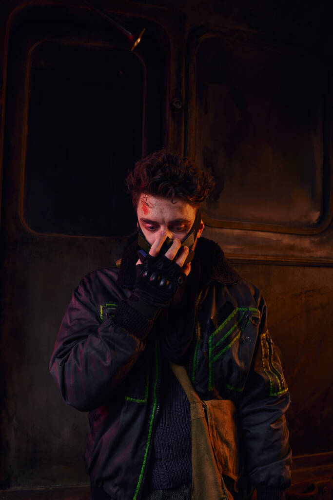 человек с поцарапанным лицом в противогазе в токсичной среде метро, последствия катастрофы - Фото, изображение