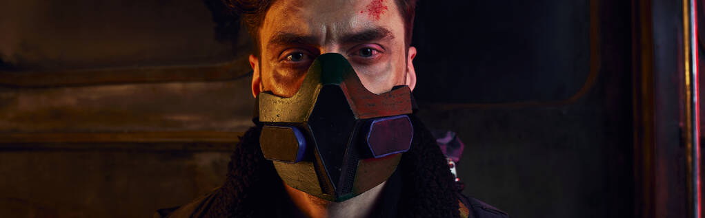 retrato del hombre con la cara arañada con máscara de gas en la oscuridad del metro post-desastre, pancarta - Foto, Imagen