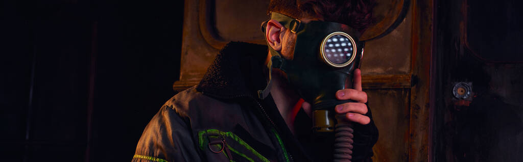 mężczyzna w masce gazowej i noszona kurtka w ciemnym podziemnym tunelu, koncepcja po katastrofie, baner - Zdjęcie, obraz