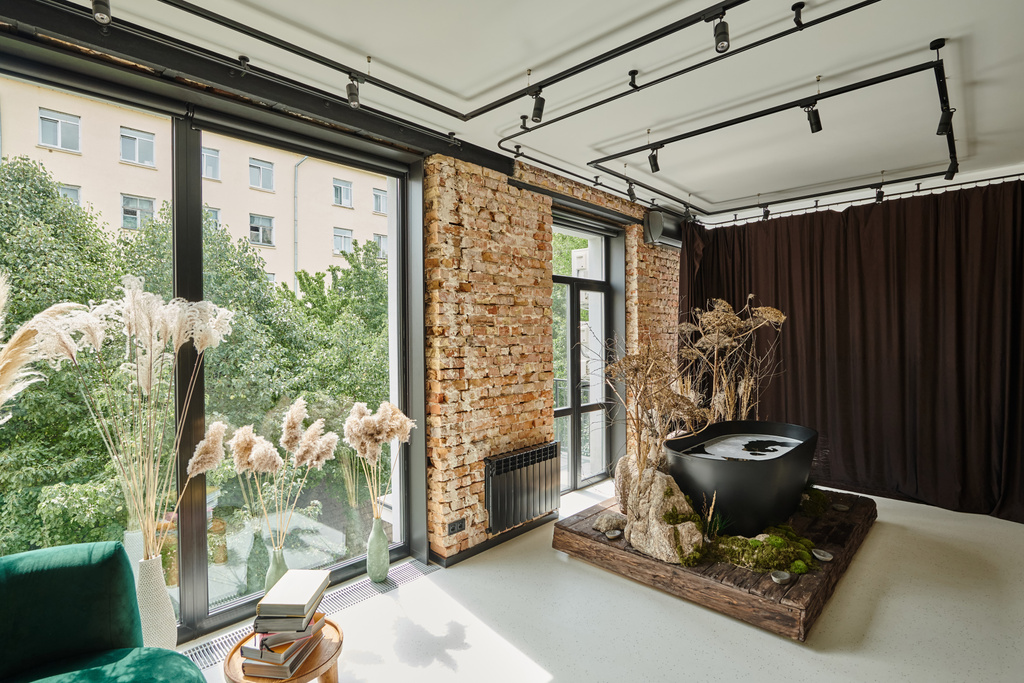 Schwarze Badewanne in einer modernen Wohnung mit Büchern auf Couchtisch, Panoramafenstern und Pflanzen - Foto, Bild