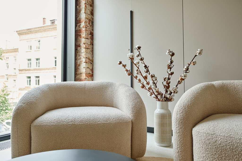 twee comfortabele en witte fauteuils naast katoenen takken in vaas, moderne woonkamer - Foto, afbeelding