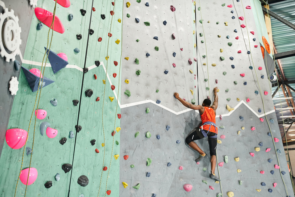 muscoloso giovane afroamericano arrampicata fino parete boulder presa fortemente sulle rocce - Foto, immagini