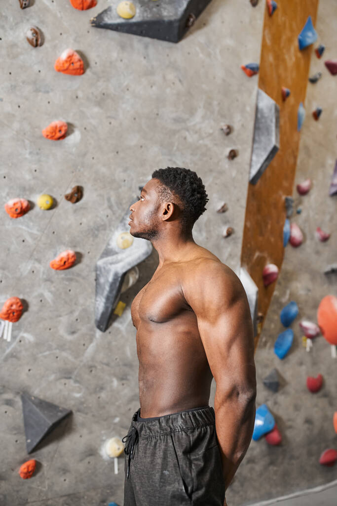 verticale colpo di bello afro americano uomo con la camicia fuori in piedi accanto alla parete di arrampicata - Foto, immagini