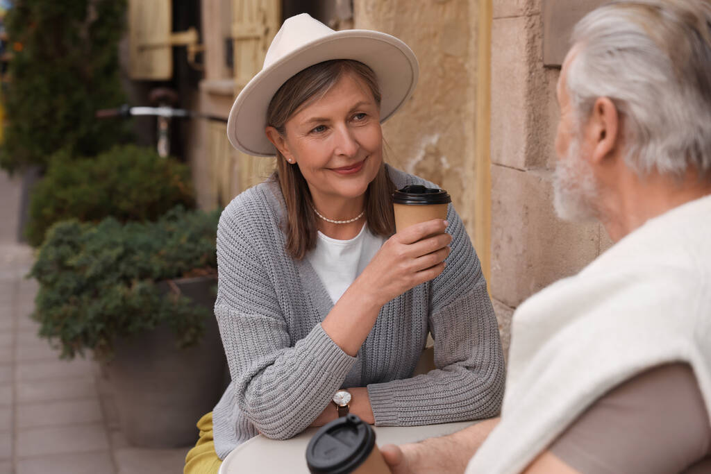 Liefdevol senior paar zitten in outdoor cafe en het drinken van koffie, ruimte voor tekst - Foto, afbeelding