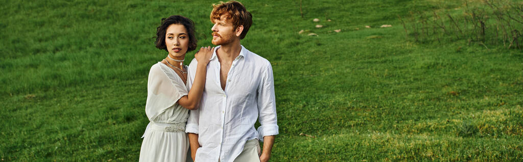 pareja interracial casada de pie juntos en el campo verde, paisaje escénico, pancarta - Foto, Imagen
