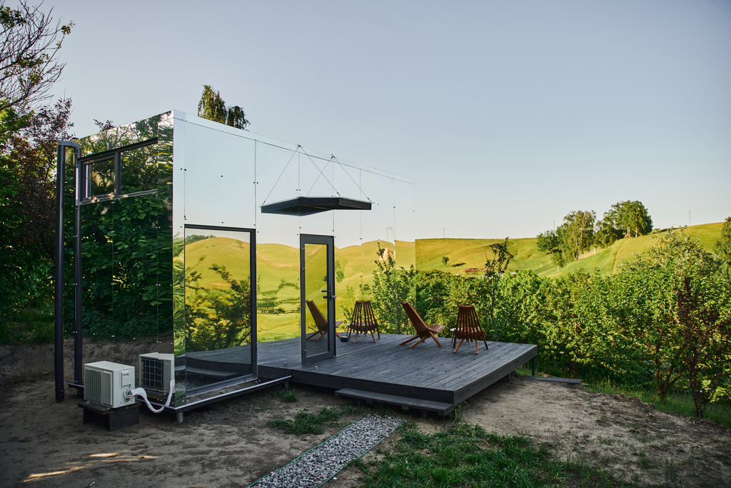 modernes minimalistisches Glashaus mit Stühlen und Couchtisch auf der Veranda, ruhige und malerische Lage - Foto, Bild
