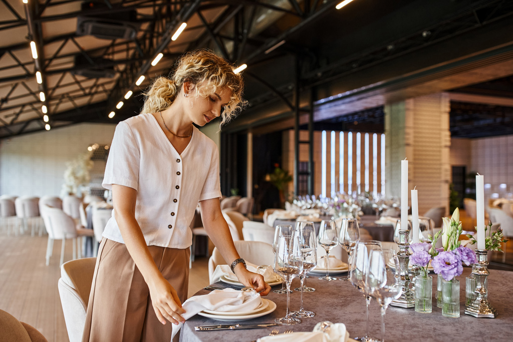décorateur blonde avec cheveux ondulés arrangement banquet sur la table avec décor floral dans la salle d'événements - Photo, image