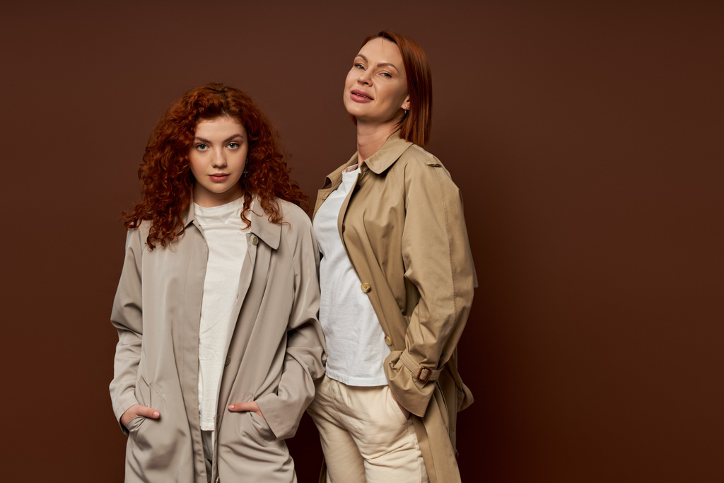 deux générations, femmes rousses en tenue d'automne tendance posant sur fond brun, trench coats - Photo, image