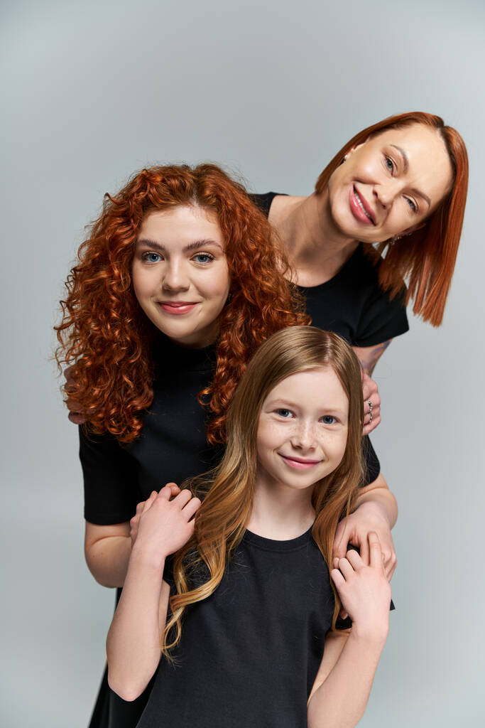 ženské generace koncept, šťastná rodina s rudými vlasy pózování v odpovídající oblečení na šedém pozadí - Fotografie, Obrázek
