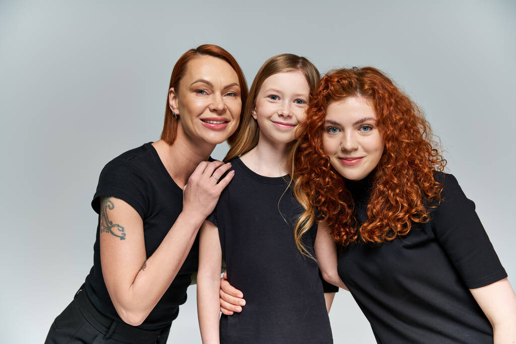 családi portré, szeplős lány mosolygós közelében vörös hajú család megfelelő öltözékben szürke háttér - Fotó, kép