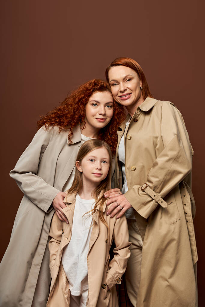 три поколения, веселые женщины и девушка, позирующая в осенних трико на сером фоне, мода - Фото, изображение