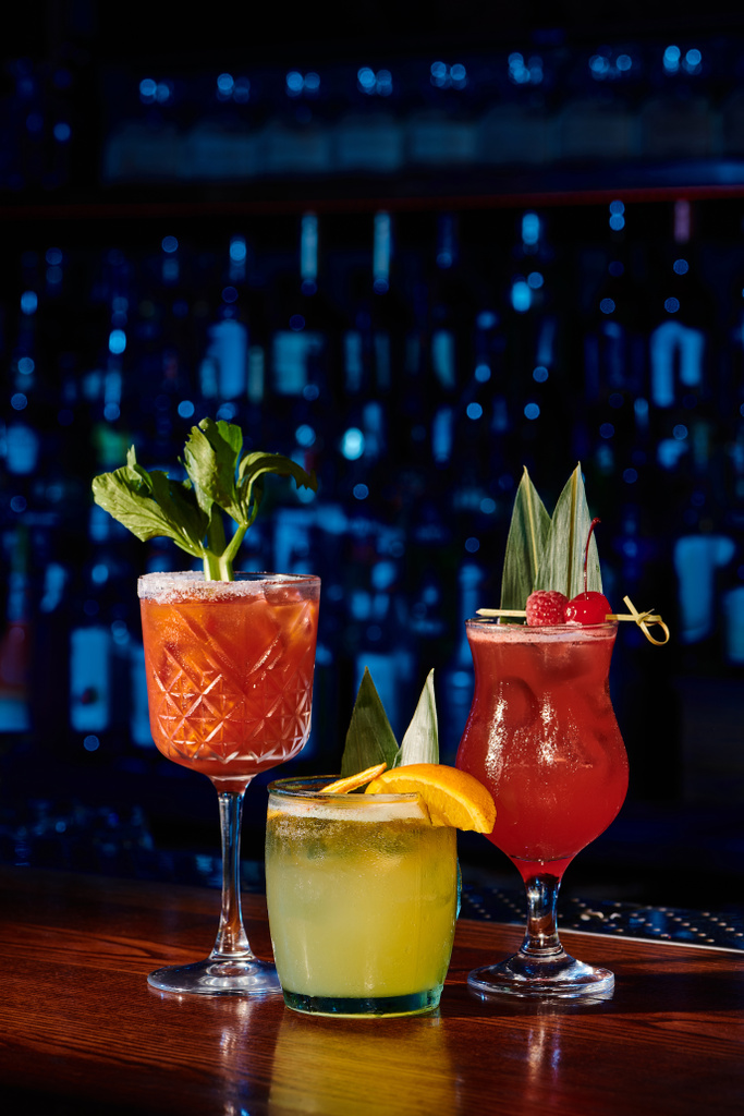 kolme virkistävää cocktaileja hedelmiä ja kasveja koristeet baari taustalla, konsepti - Valokuva, kuva