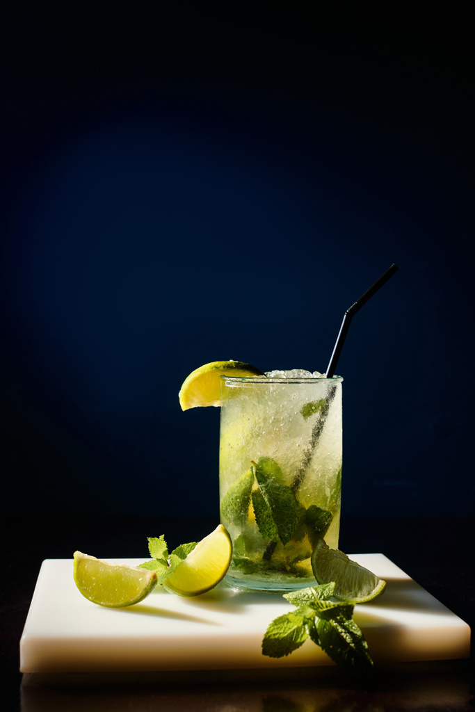 thirst quenching cold mojito garnished with mint leaves and lime on black backdrop, concept - Photo, Image