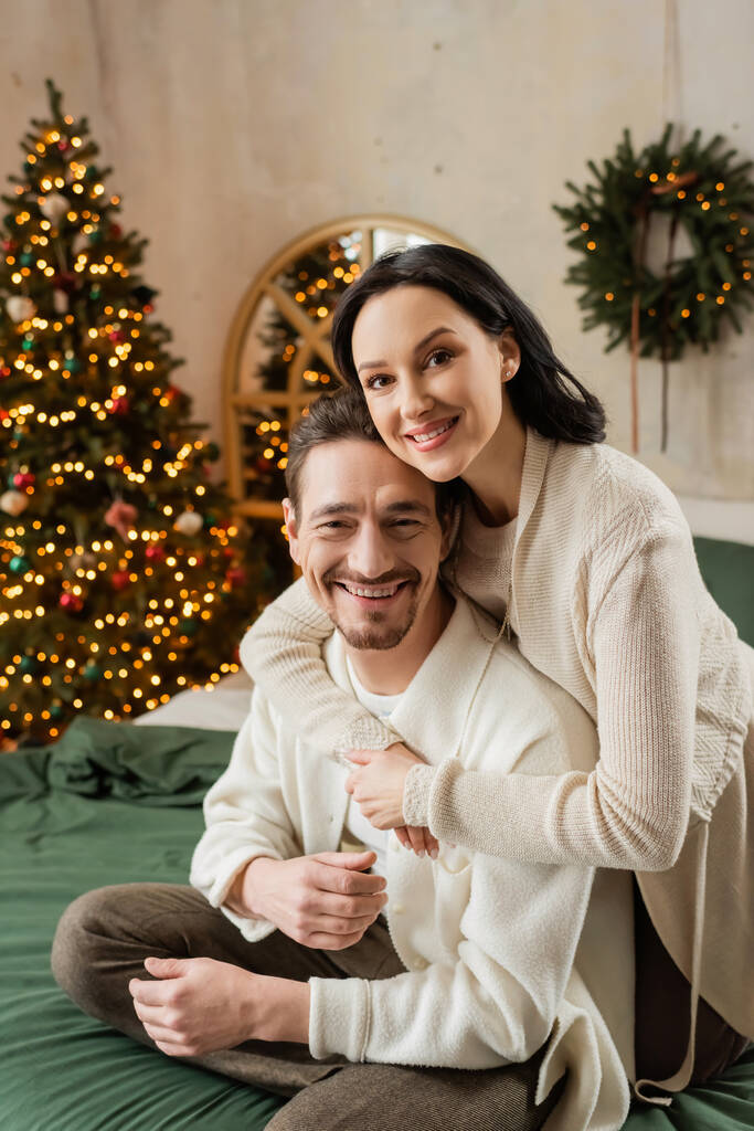 onnellinen nainen halaus parrakas aviomies lähellä hämärtynyt joulukuusi modernissa asunnossa, tyytyväisyys - Valokuva, kuva