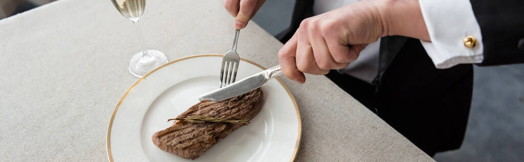 felső kilátás férfi szmokingban vágás finom marhahús steak tányéron közel üveg pezsgő, banner - Fotó, kép
