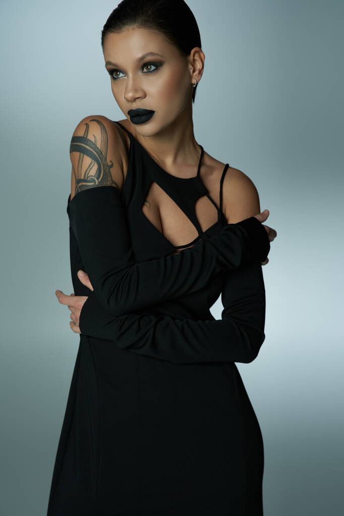 tajemnicze tatuaż kobieta z czarodziejka makijaż pozowanie w czarny sukienka na szary, halloween pojęcie - Zdjęcie, obraz