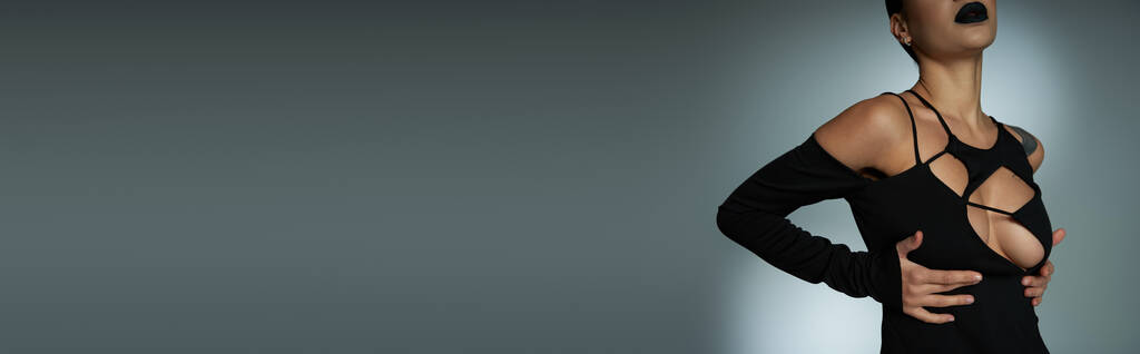обрізаний вид стильної спокусливої жінки в чорному костюмі на Хеллоуїн на сірій, готичній красуні, банер - Фото, зображення