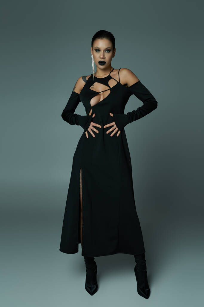 plná délka okouzlující žena v černých kouzelnických šatech a make-up na šedé, halloween koncept - Fotografie, Obrázek