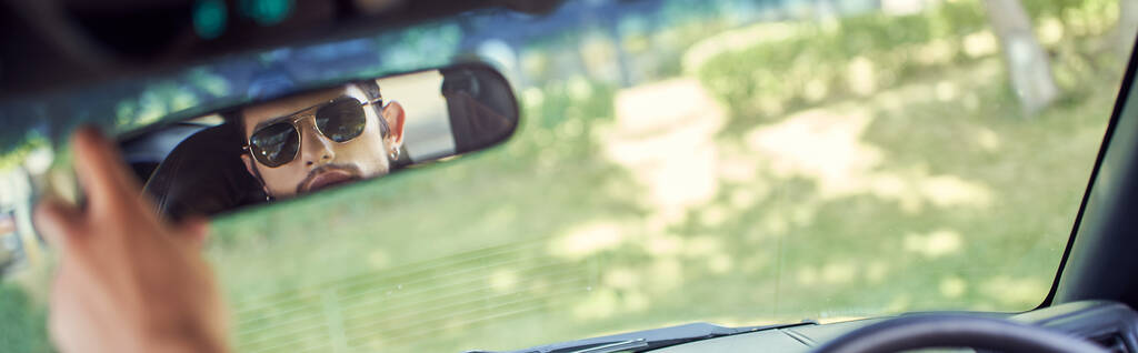 good looking young sexy man with stylish sunglasses looking at his rearview mirror, banner - Фото, изображение