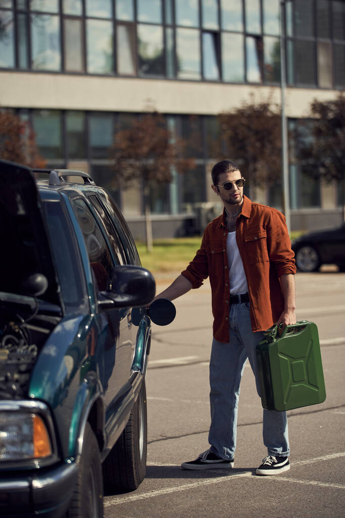 bonito sexy masculino modelo no marrom camisa e jeans com elegante óculos de sol reabastecendo seu carro - Foto, Imagem