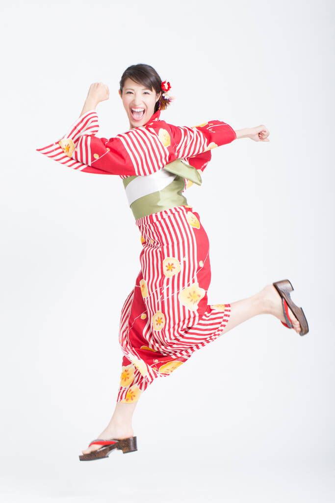 Mujer asiática usando kimono japonés tradicional corriendo sobre fondo blanco del estudio - Foto, Imagen