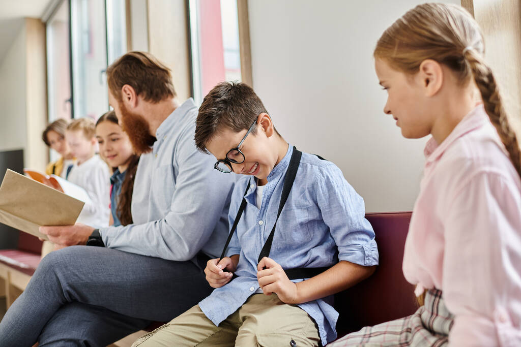 En un salón de clases luminoso y animado, un maestro instruye a un grupo diverso de niños que están sentados uno al lado del otro con atención. - Foto, Imagen