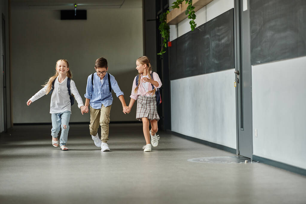 Un grupo de niños, caminando por un pasillo iluminado en una escuela. - Foto, imagen