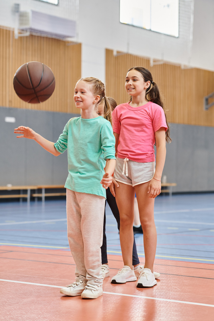 Mädchen stehen selbstbewusst auf einem Basketballfeld und hören aufmerksam den Anweisungen ihrer männlichen Lehrer zu. - Foto, Bild