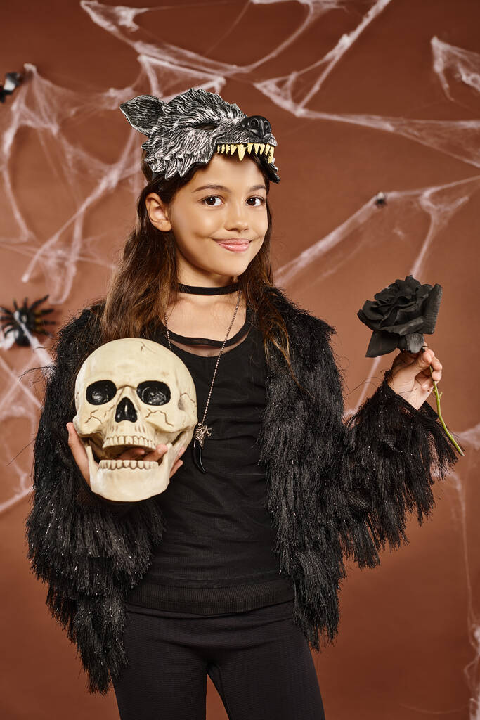 lähikuva hymyilevä preteen tyttö pitää musta ruusu ja kallo käsissään yllään susi naamio, Halloween - Valokuva, kuva
