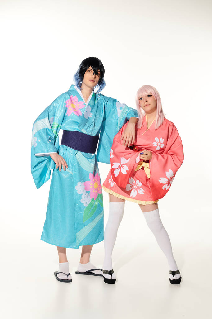 pleine longueur de jeune et dynamique couple en kimonos et perruques sur blanc, asiatique cosplay sous-culture - Photo, image