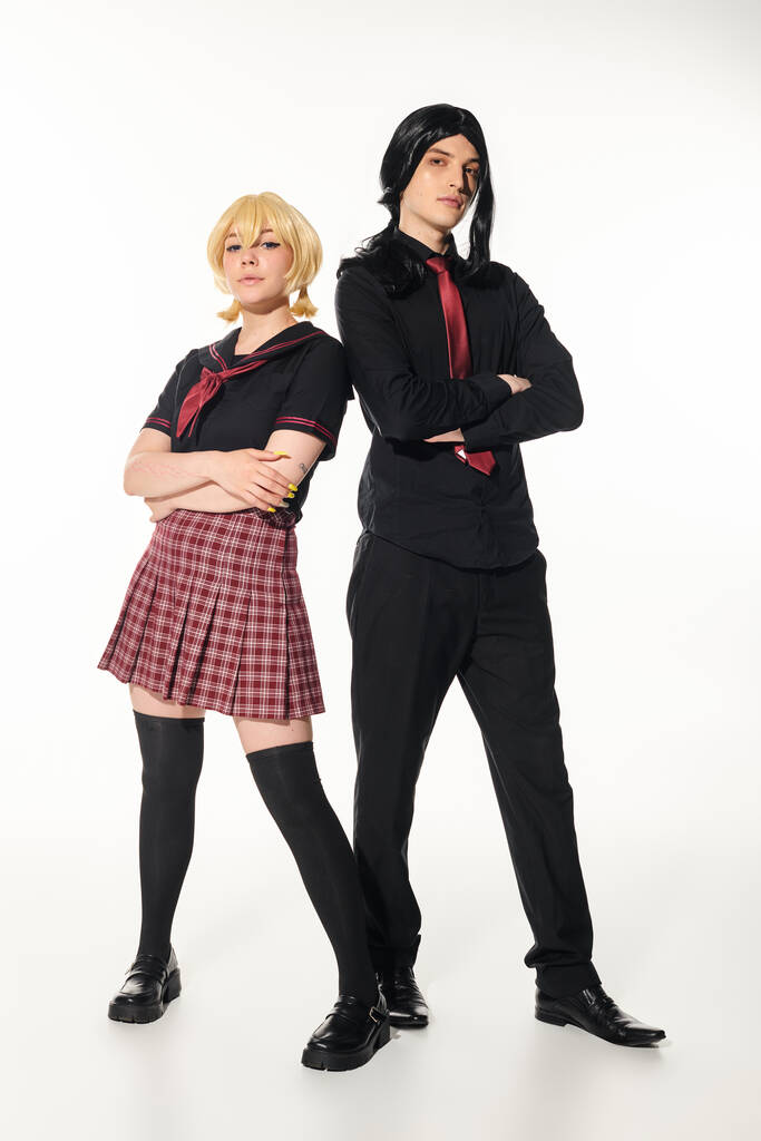 full length of young cosplayers in school uniform and wigs posing with folded arms on white - Photo, Image
