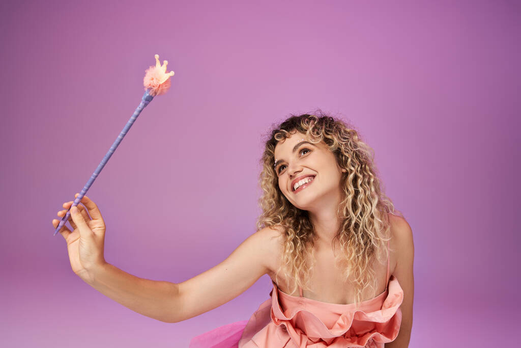 verträumte attraktive Frau im rosa Kleid, Zauberstab in der Hand und wegschauend, Zahnfee-Konzept - Foto, Bild