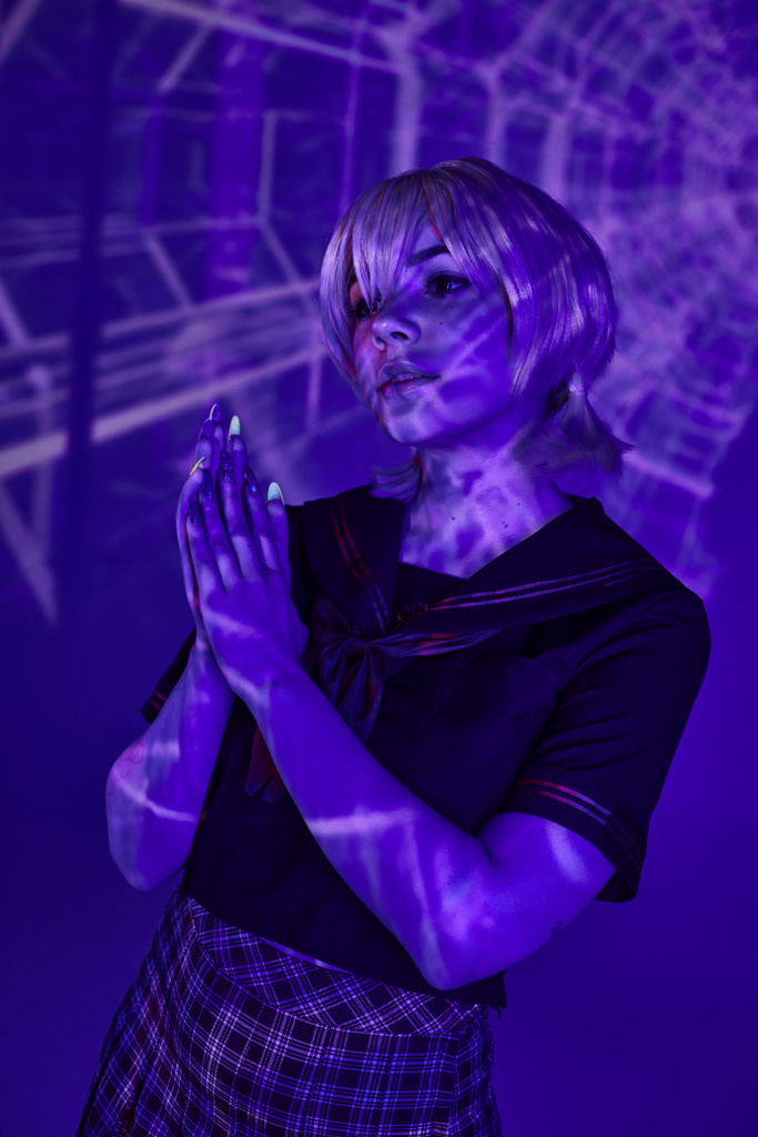 mulher cosplay loira em uniforme escolar de pé com as mãos de oração em projeção abstrata azul - Foto, Imagem