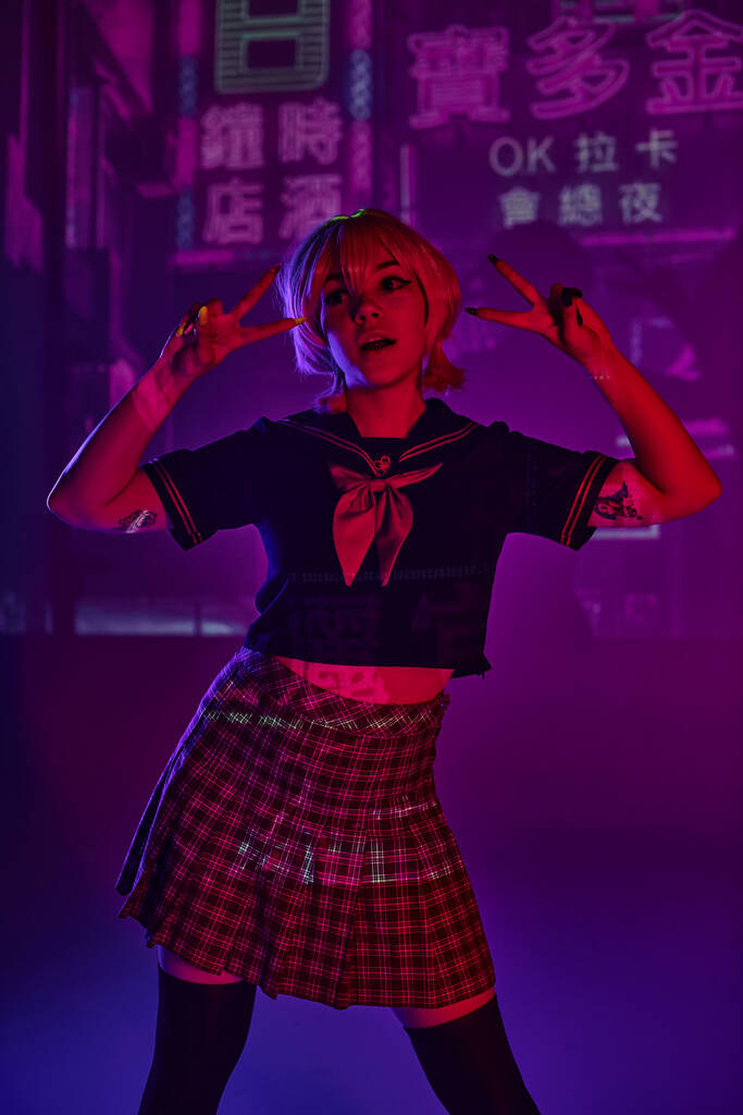 anime donna in uniforme scolastica che mostra segni di vittoria su sfondo viola al neon con geroglifici - Foto, immagini