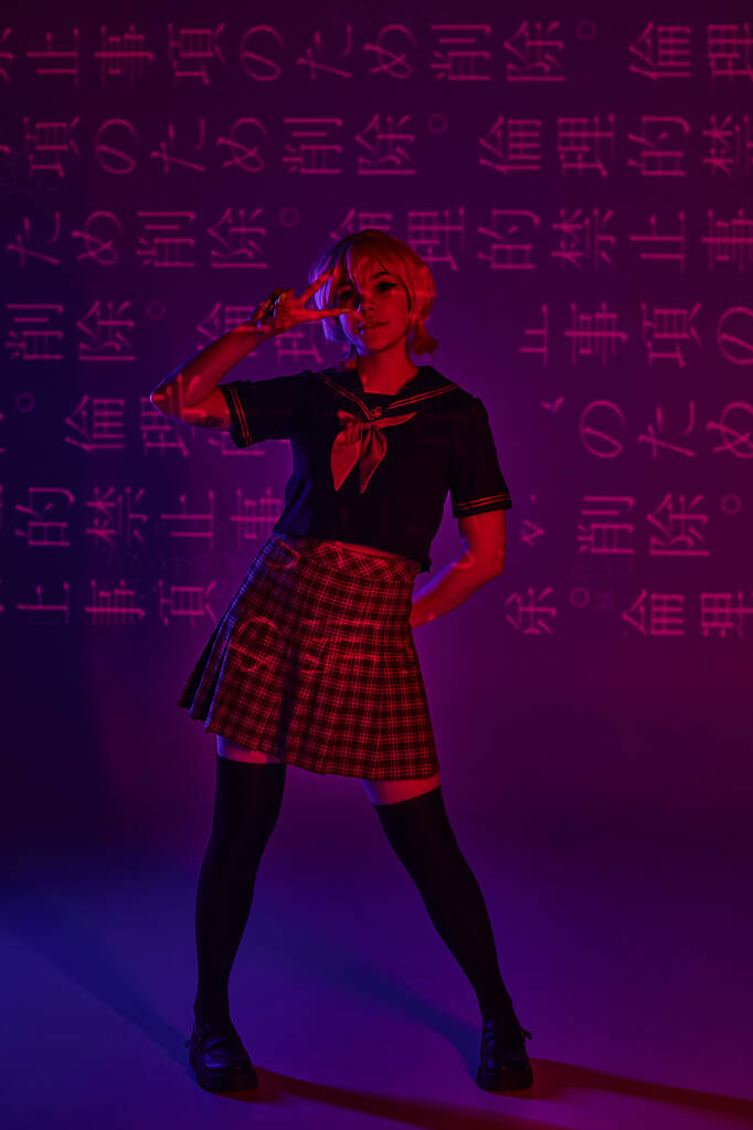trendy anime vrouw in school uniform tonen overwinning teken op neon paarse achtergrond met hiërogliefen - Foto, afbeelding