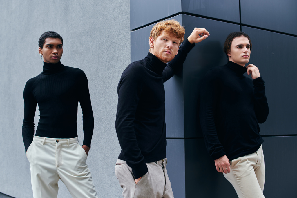 trzech przystojnych młodych mężczyzn w czarnych golfistach pozujących ze ścianą na tle, koncepcja mody - Zdjęcie, obraz