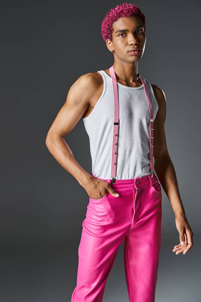 roze harig jong mannelijk model poseren op grijze achtergrond met een hand in zak, mode en stijl - Foto, afbeelding