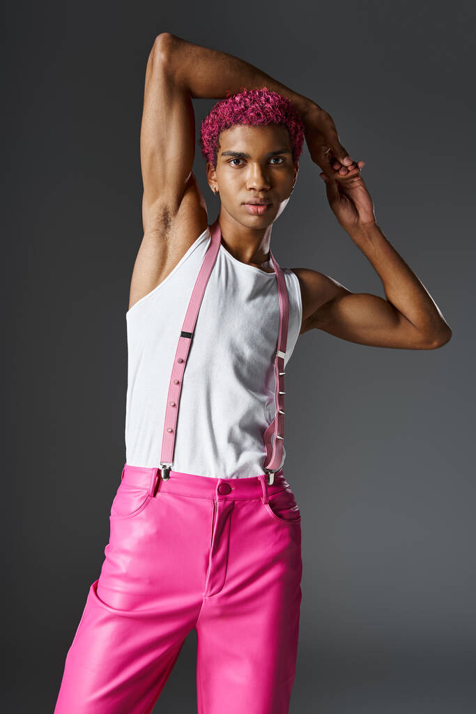 стильний чоловік в рожевих штанях з підтяжками, руки за голову дивляться на камеру, моду і стиль - Фото, зображення