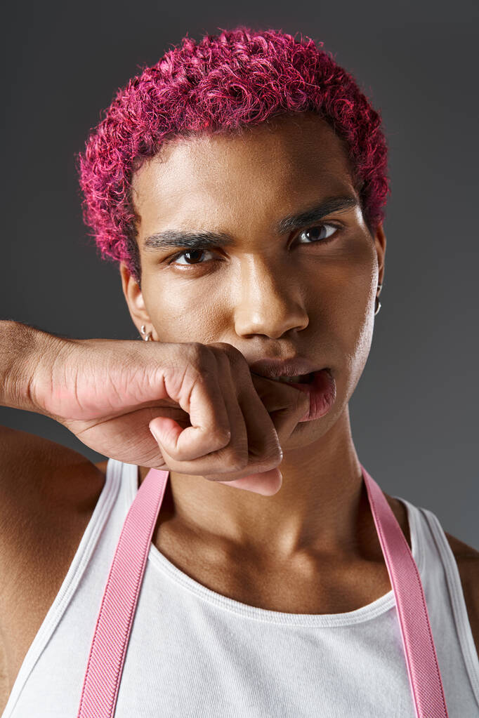 портрет серйозного рожевого волосистого чоловіка з кулаком біля обличчя, дивлячись на камеру, моду і стиль - Фото, зображення