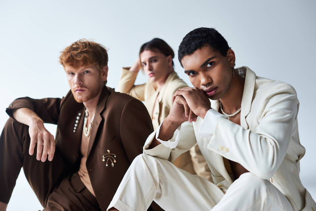 enfoque en amigos interracial cerca borrosa joven en trajes de voguish sentado en el suelo, poder de los hombres - Foto, imagen