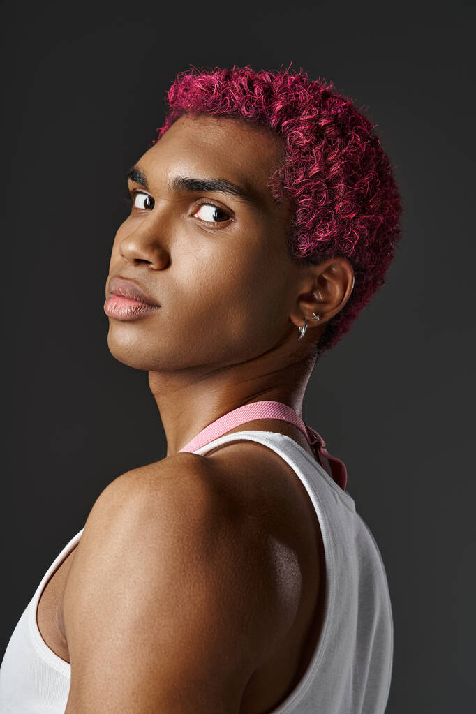 Porträt eines gutaussehenden jungen Mannes mit rosa Haaren, der vor grauem Hintergrund in die Kamera blickt, Modekonzept - Foto, Bild