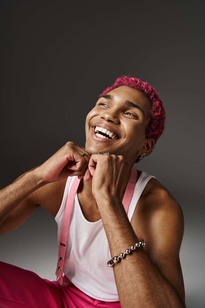 όμορφος κομψός άντρας με ροζ μαλλιά κρατώντας τα χέρια κάτω από το πηγούνι και χαμογελώντας ειλικρινά, μόδα έννοια - Φωτογραφία, εικόνα