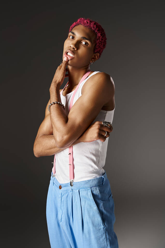 uomo afroamericano dai capelli rosa con un dito sulle labbra e braccia incrociate su sfondo grigio, moda - Foto, immagini