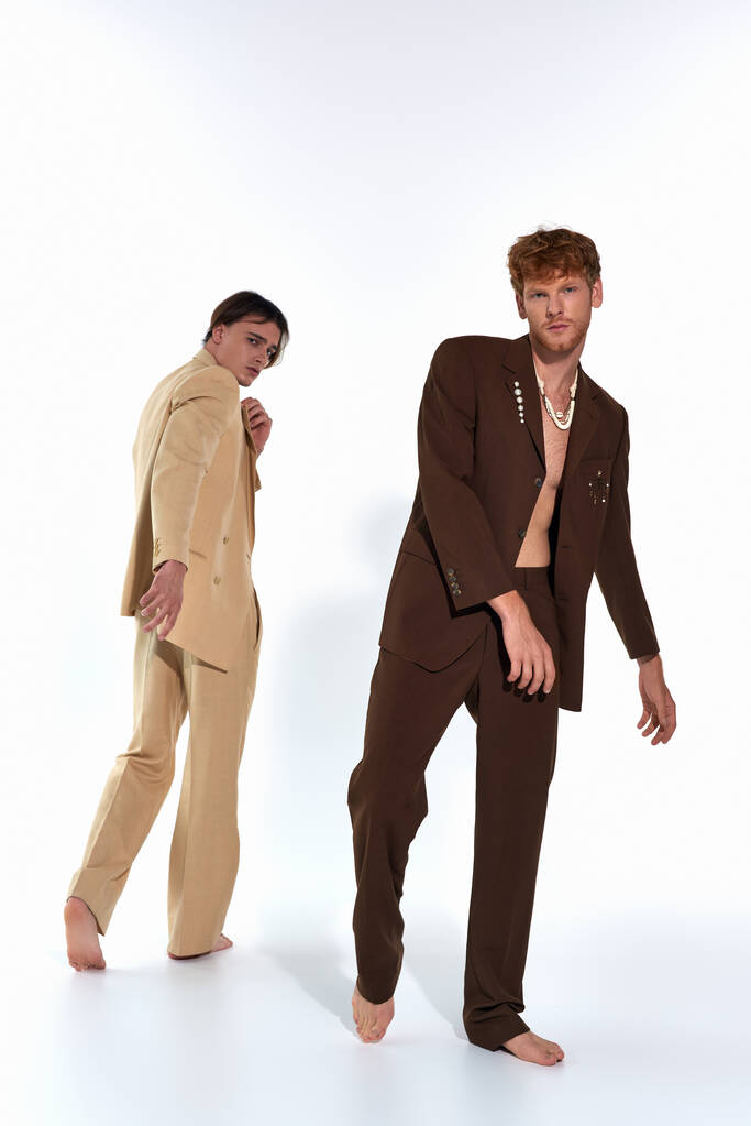 дві гарні молоді чоловічі моделі в стильних костюмах позують в русі на білому тлі, чоловіча влада - Фото, зображення