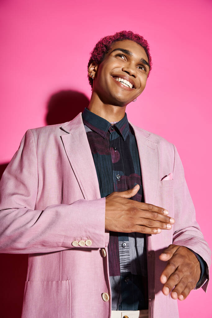 stylish african american man gesturing unnaturally smiling and posing on pink backdrop, doll like - Photo, Image