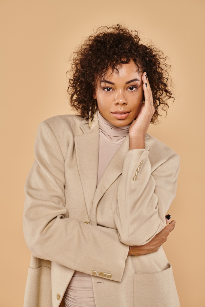 autunno moda, elegante donna africana americana in posa in dolcevita e blazer su sfondo beige - Foto, immagini