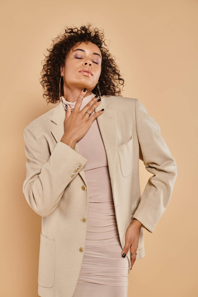 autunno moda, bruna afro-americana donna con gli occhi chiusi in posa in dolcevita e blazer - Foto, immagini