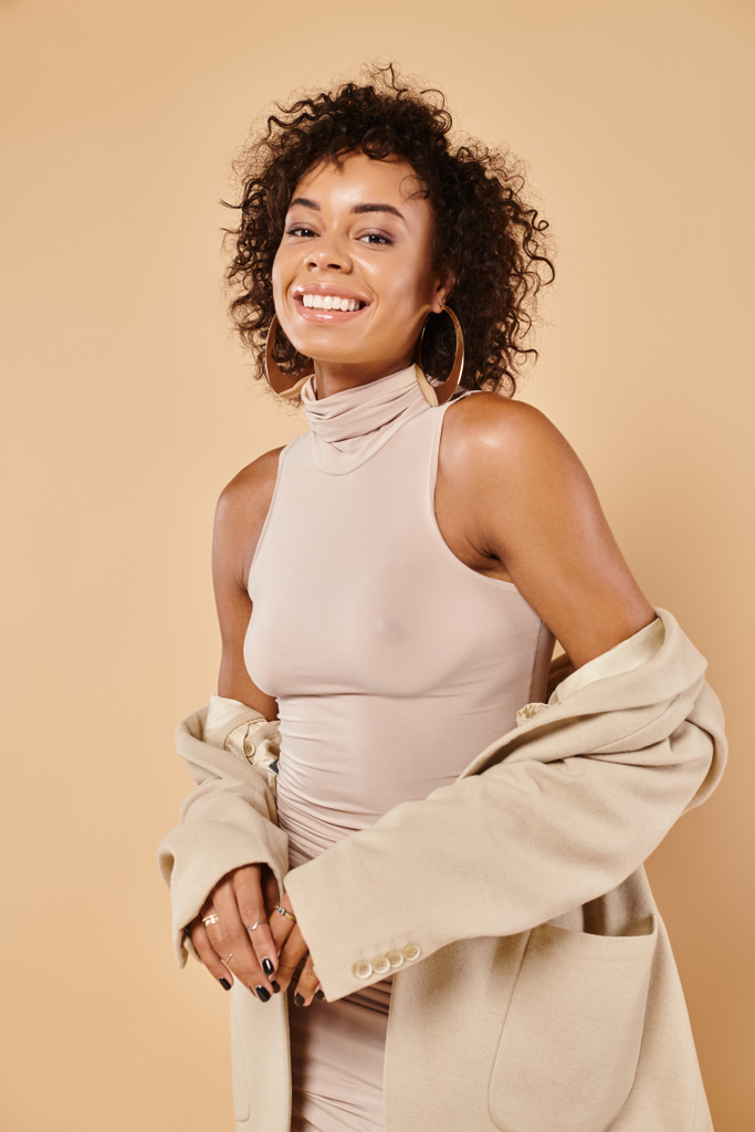 tendenze autunnali, piacere donna afro-americana in posa in blazer e abito stretto su sfondo beige - Foto, immagini